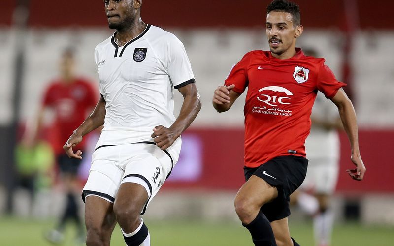 Two players chase the ball in a Qatar Stars League match